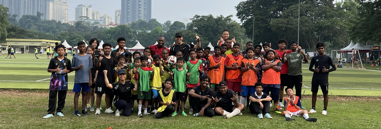 The full Beyond 90 squad of around 40-50 children and coaches, KL skyline behind